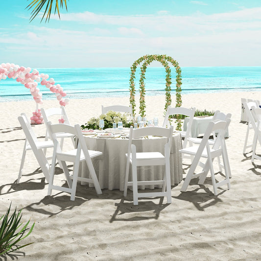 Set of four white portable resin folding chairs with padded seats for comfortable event seating